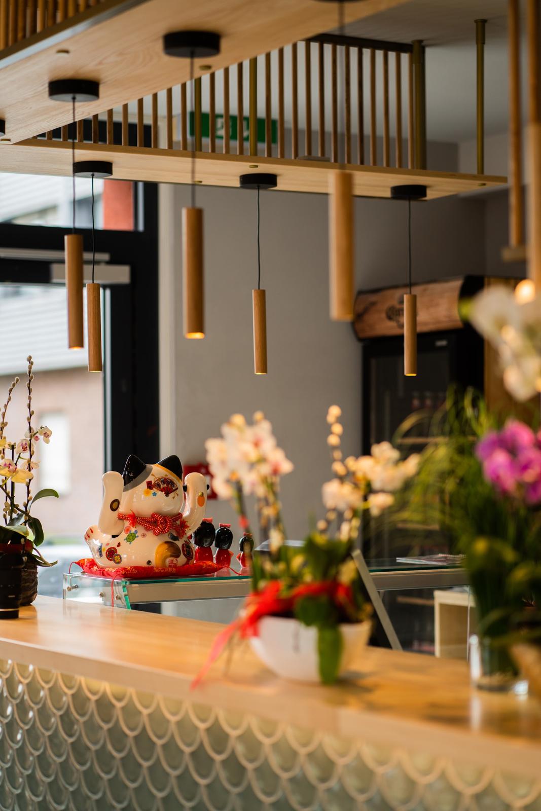 Winkende Glückskatze und Orchideen auf der Theke