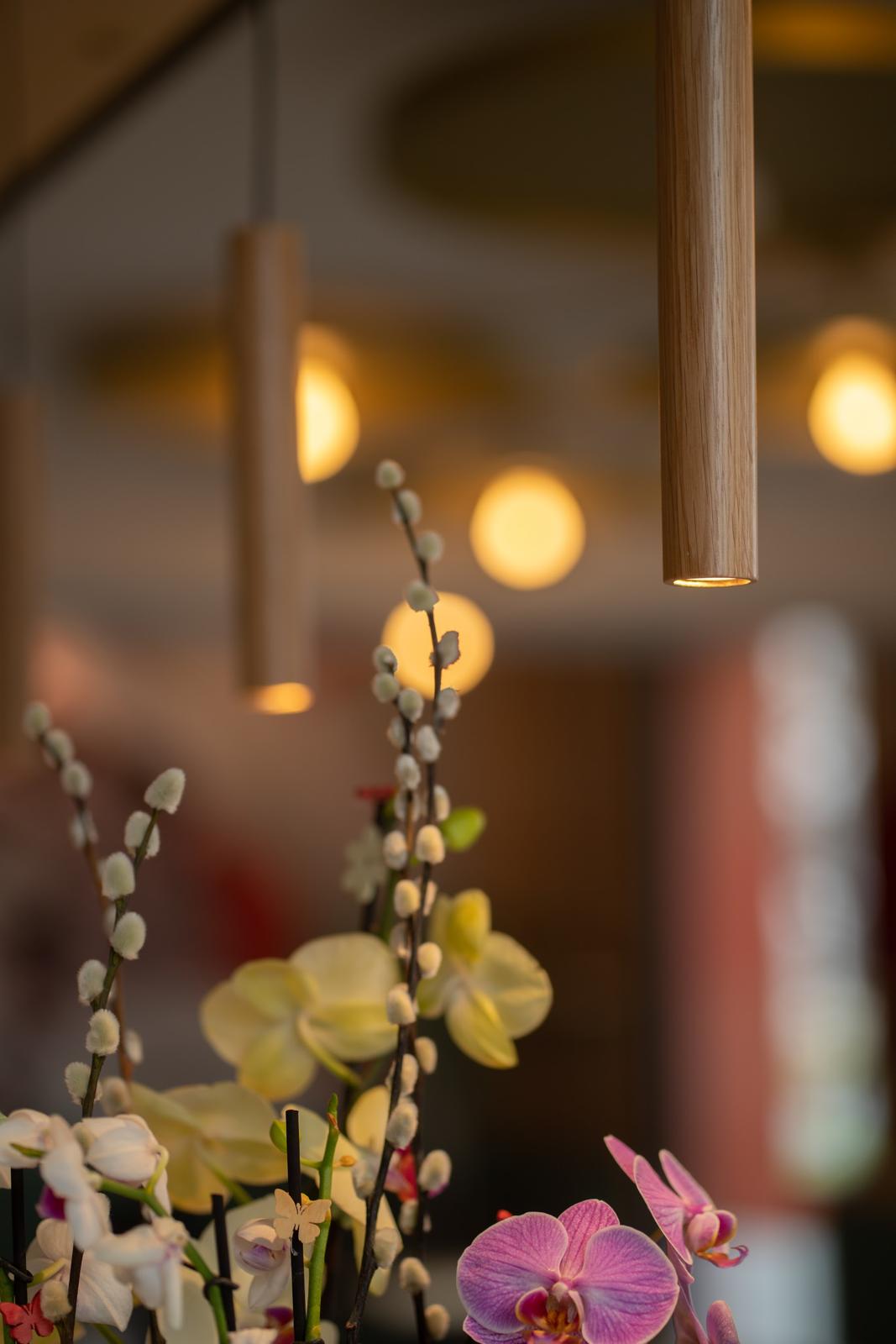 Holz-Pendelleuchten über Orchideen und Weidenkätzchen